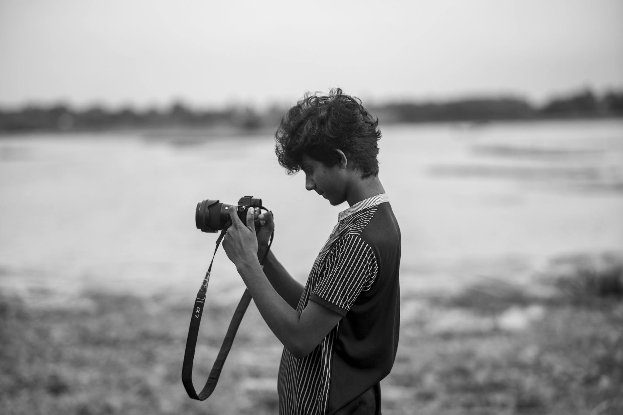 A young photographer using a camera in an outdoor setting near Dhaka, Bangladesh.