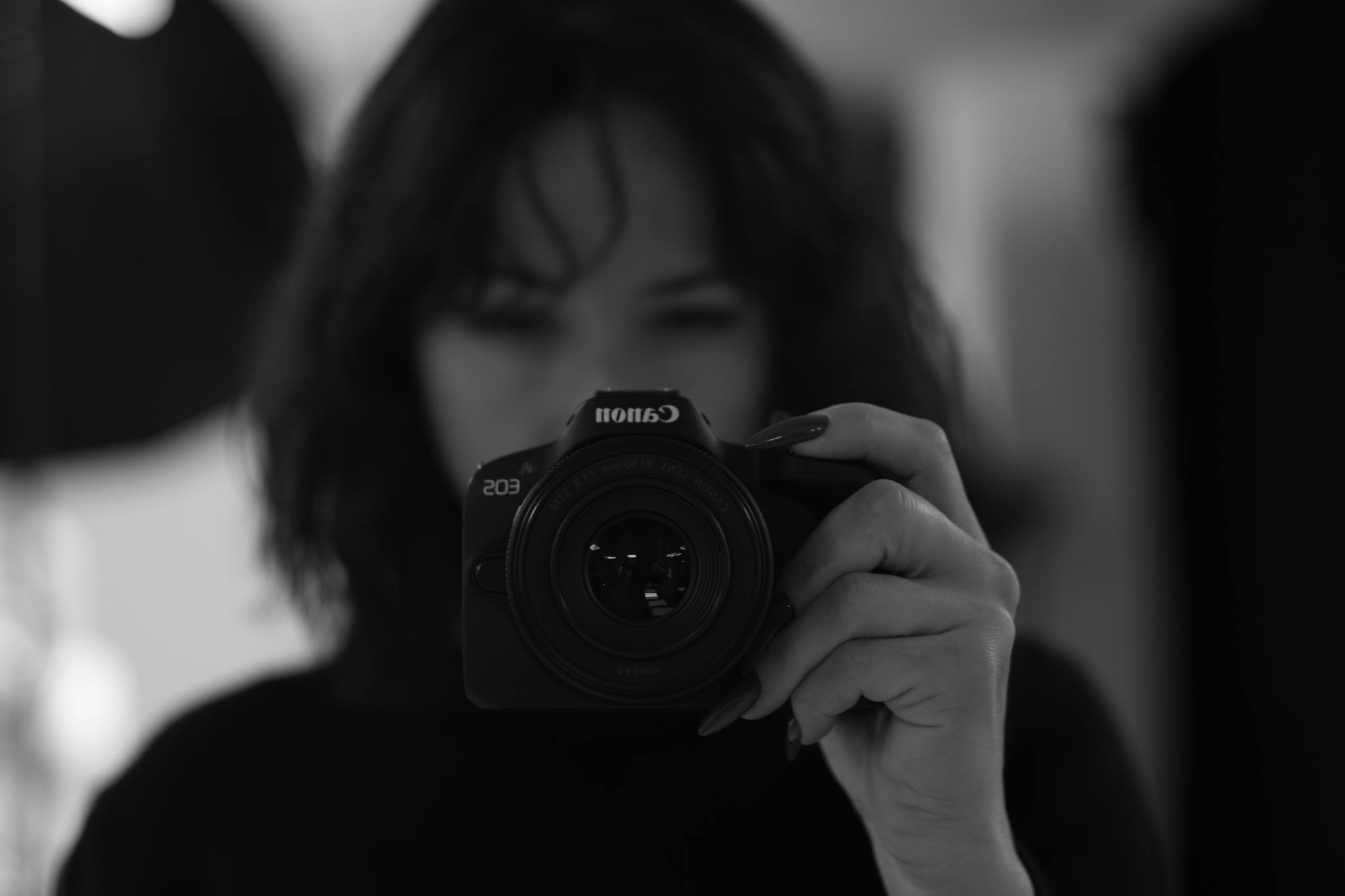 Artistic black and white portrait capturing a self-portrait using a DSLR camera.
